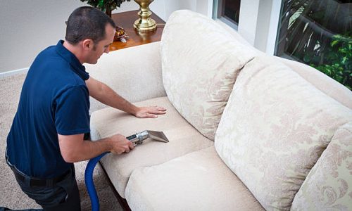 Man cleaning sofa pillow with steam cleaning in home